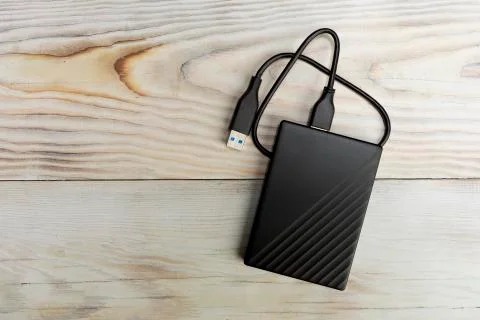 External compact SSD-drive with USB cable on wood background Stock Photos