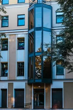 External glass elevator shaft on beige apartment building facade Stock Photos