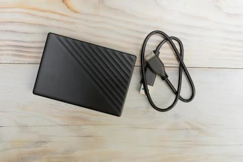 External hard drive for storing memory with wire on wood table Stock Photos