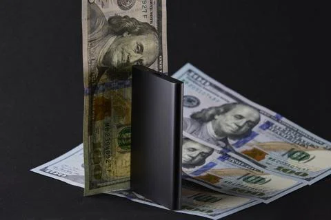 External solid state drive standing among US dollar and euro banknotes on b.. Stock Photos