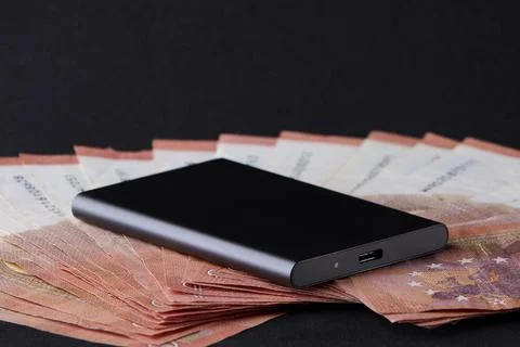 External SSD drive placed on spread euro bills representing financial techn.. Stock Photos