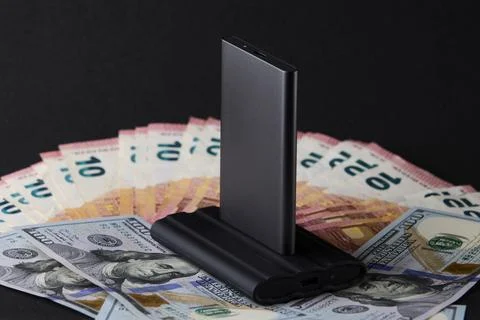 External SSD drive on stack of euro and dollar cash symbolizing global financ Stock Photos
