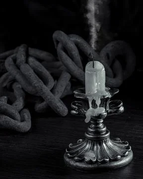 Extinct candle in chains on a wooden table. 스톡 사진