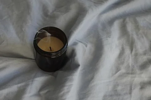 Extinguished candle on the bed close-up. Stock Photos