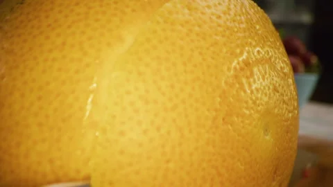 Extra closeup of knife slicing through beautiful, juicy orange in kitchen Vídeo Stock 341247366