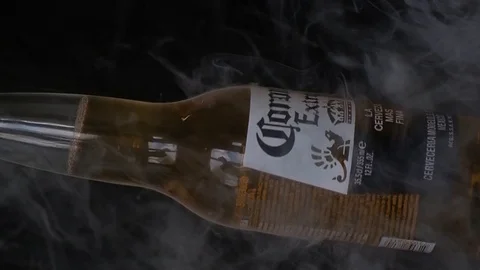 Extra Corona beer bottle spinning on a black background with smoke. Stock Footage 126176673