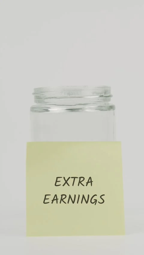 Extra earnings text or word on yellow sticky note attached to glass jar Stock Footage 311730598