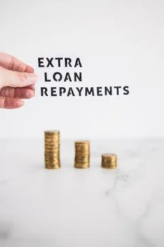 Extra loan payment text in front of decreasing stacks of coins, paying down y 写真素材