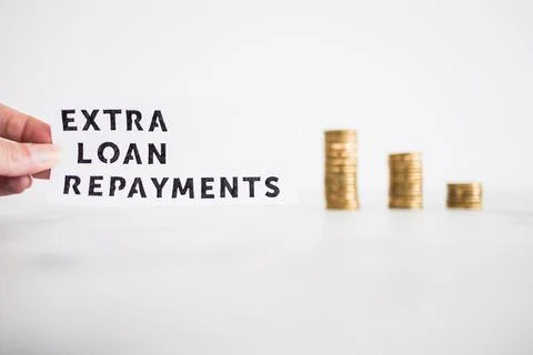 Extra loan payment text in front of decreasing stacks of coins, paying down y Foto stock