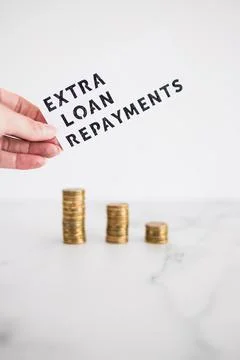 Extra loan payment text in front of decreasing stacks of coins, paying down y Foto stock