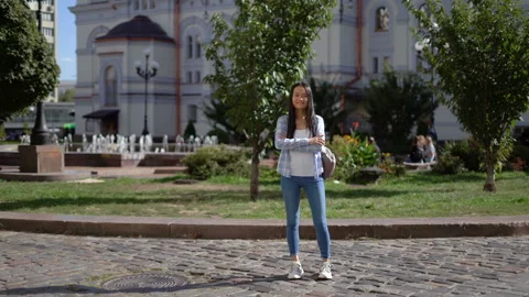 Extra long shot. beautiful slender asian woman stands on the street with her Stock Footage 140763826