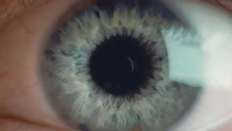 Extra macro shot of man's opening eye with blue iris and big black tapering Stock Footage 136474370