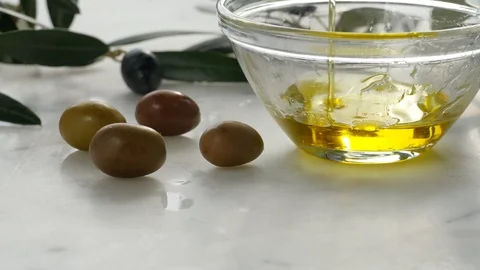 Extra Virgin oil falls on transparent bowl, white background. Genuine Italian in Stock Footage 122494847