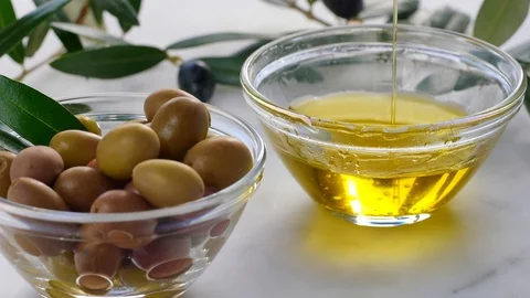 Extra Virgin oil falls on transparent bowl, white background. Genuine Italian in Stock Footage 122495452