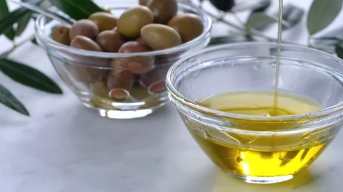 Extra Virgin oil falls on transparent bowl, white background. Genuine Italian in Stock Footage 122495482