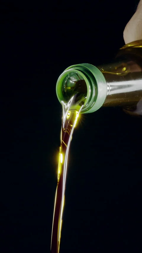 Extra virgin olive oil is being poured out from a bottle. Stock Footage 325984476