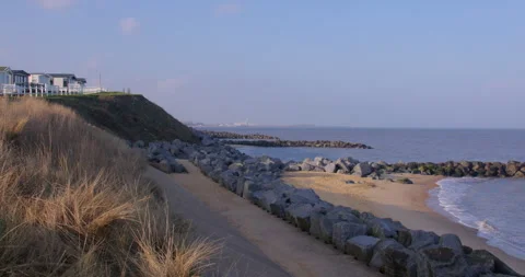 Extra wide zoom shot of rock Groynes, sea wall and marram grass, at Hopton Stock Footage 341603447