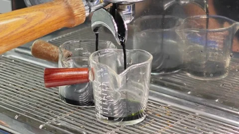 Extracting a fresh matcha green tea shot into a glass cup with wooden handle. Vidéo 344747282