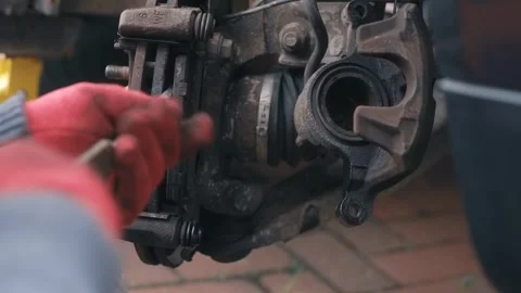 Extracting worn brake pad with gloved hands for inspection and replacement Stock Footage 335368840