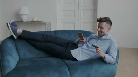 Extraordinary and handsome man lying on the sofa in footwear in comfortable Stock Footage 107788260