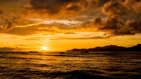 Extraordinay gold sunset with dramatic clouds in a tropical island, Anse Seve Stock Photos