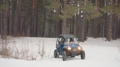 Extreme atv driving through snowy pine woods, headlights on, steady trail pace Video stock 345147214