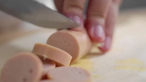 Extreme close-up and selective focus of woman's hands cutting sausages on a.. Stock Footage 329703639