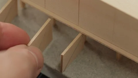 Extreme close up of architect's hands placing a door on a wood scale model Video stock 104442076