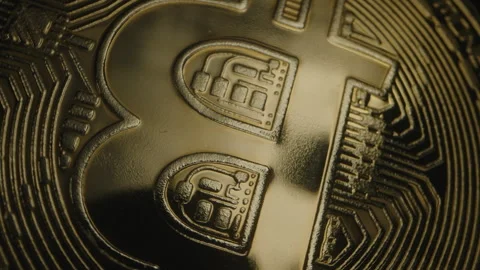 Extreme Close-Up of Bitcoin Coin, Focused on Its Textured Logo and Intricate Stock Footage 296504830