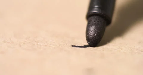 Extreme close-up of black marker tip contacting textured brown paper leaving Stock Footage 303624810