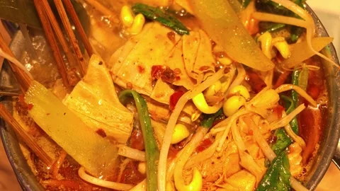 Extreme Close-up of Boiling Spicy Hot Pot with Vegetables and Tofu in Metal Bowl Vidéo 344853277