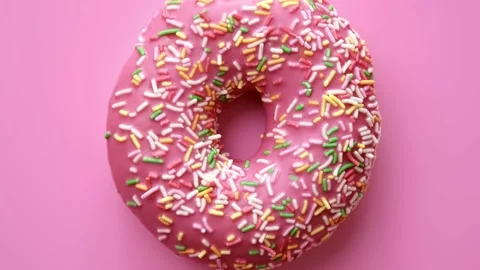 Extreme close up bright circle donut covering by icing glaze isolated on pink Video stock 152505905