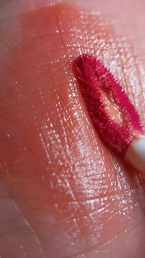 Extreme close up of brush applying pink lip tint on skin surface. Pigment b.. Video stock 346828343