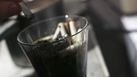 Extreme close-up, camera zooming in on hand extinguishing cigarette in glass ash Stock Footage 224296418