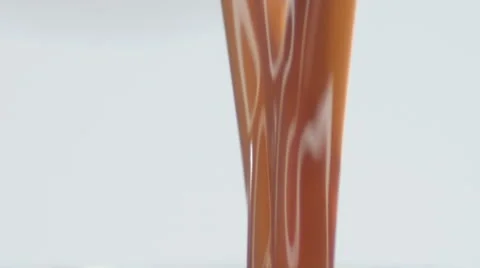 Extreme close up of caramel-colored liquid streaming down Vidéo 52323831