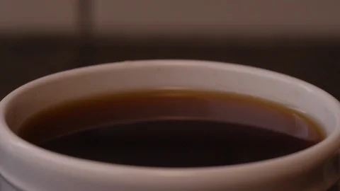 Extreme close-up of a drop into a filled cup of coffee in slow motion Video stock 127226946