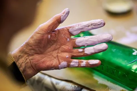 Extreme close up of an elderly person's hand covered in purple paint during a Foto stock