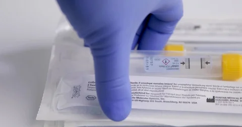 Extreme Close Up of Gloved Heathcare Worker Picking up COVID Swab Kit Stock Footage 129416348