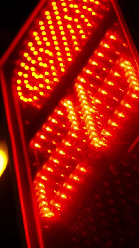Extreme close-up of glowing red LED vehicle taillight with arrow-shaped pattern Stock Footage 329555519
