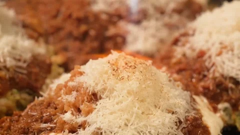 Extreme Close-Up of Grated Parmesan Cheese Melting on Large Gourmet Italian Meat Stock Footage 333522089