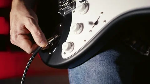Extreme Close-up of Hand Plugging Cable into Electric Guitar. Musician conn.. Video stock 331971327
