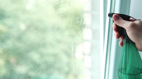 Extreme close up of a hand spraying detergent on dirty window glass from a .. Stock Footage 340159289