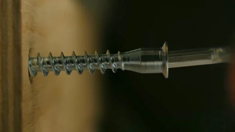 Extreme close-up of hexagon bolt being screwed into furniture joint with precise Stock Footage 312845594