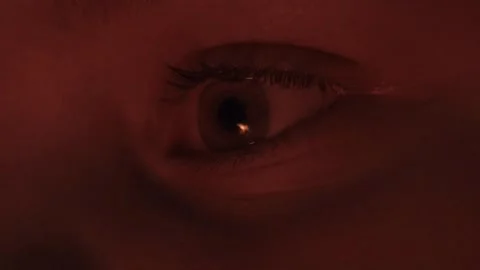 Extreme close up of human eye blinking in red atmospheric light Stock Footage 334572384