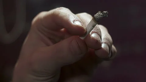 Extreme close-up of igarette filter butt being sprinkled with ashes in hand.. Stock Footage 224298812