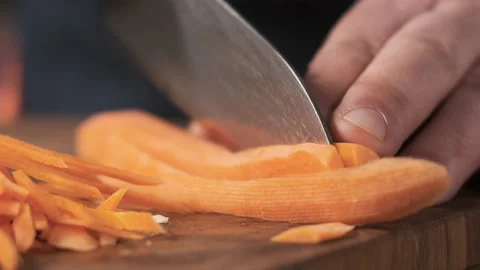 Extreme close up macro chef in restaurant kitchen cuts carrot with sharp, shiny Stock Footage 150665541