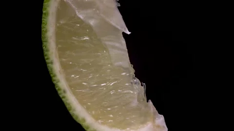 Extreme close up macro slice of sour juicy lime rotate or spin on black Stock Footage 133337407