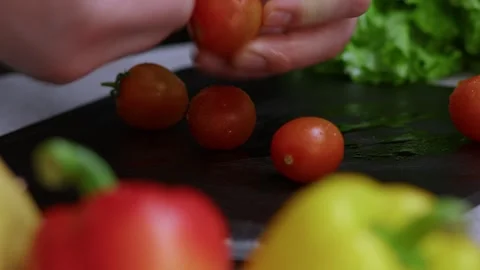 In extreme close-up, a man's strong hands peel red ripe cherry tomatoes; a cook Vidéo 273013011