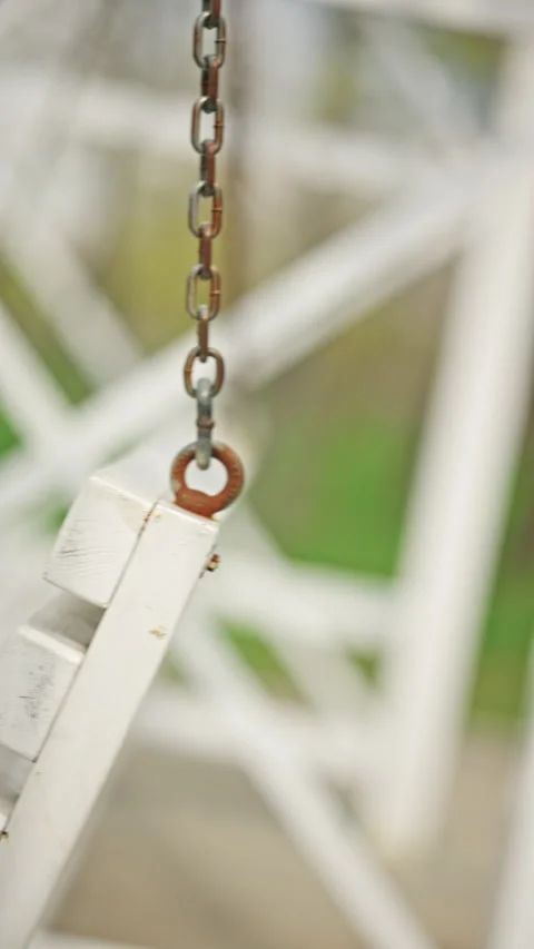 Extreme close up of a metal chain attached to a white wooden swing bench, Vidéo 335340116