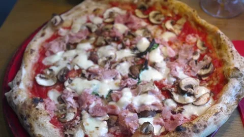 Extreme close-up Moving shot of a ham and mushroom pizza served on red a plate Stock Footage 303749754